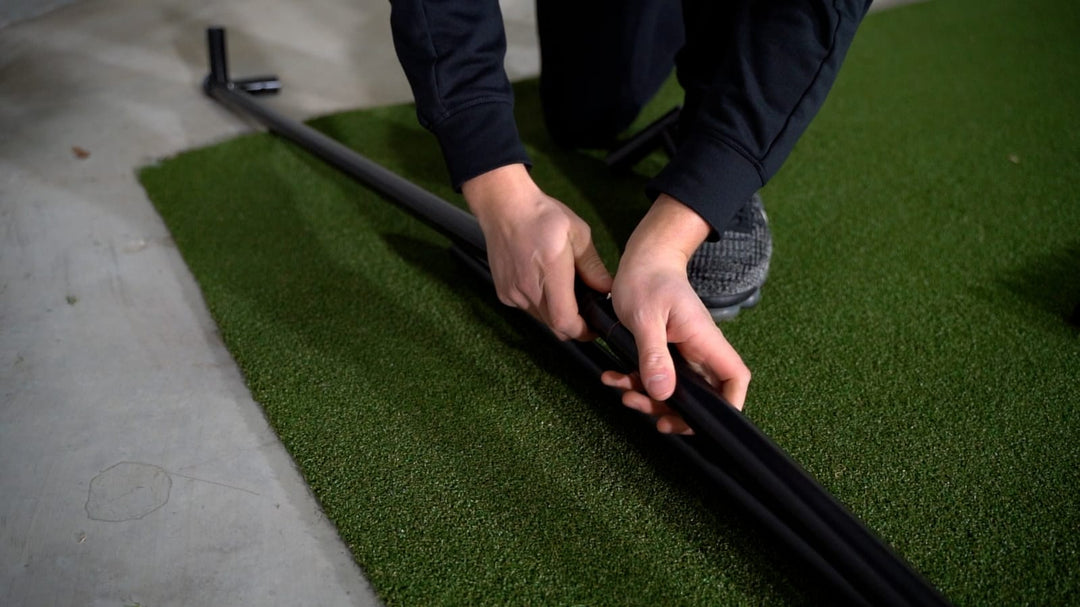 Hands joining two metal frame tubes during DIY golf enclosure assembly