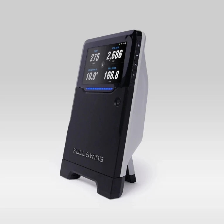 Angled view of the Full Swing launch monitor displaying carry distance, spin rate, launch angle, and ball speed data.