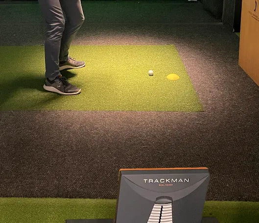 Golf simulator hitting bay lit by the LTS Jett-T LED spotlight, showing bright and even illumination for TrackMan launch monitor and hitting mat.
