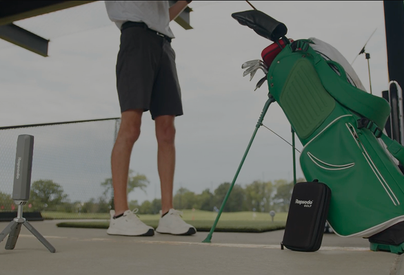 Rapsodo MLM2XPRO auf einem Stativ neben Golfer und Golftasche auf einer Outdoor-Driving-Range