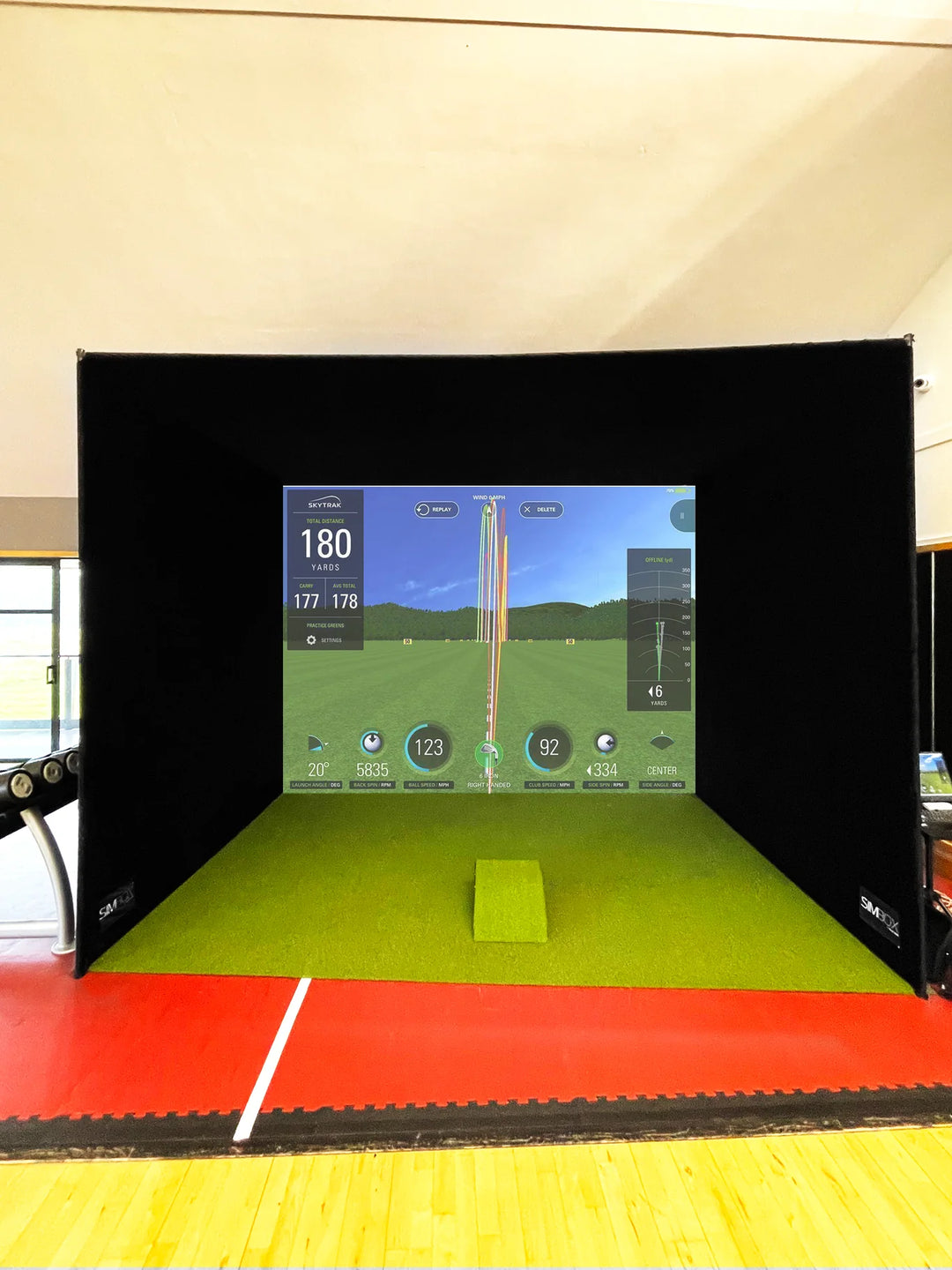Front view of the GolfBays SimBox golf simulator enclosure with impact screen and turf mat – available at Golf and Greens