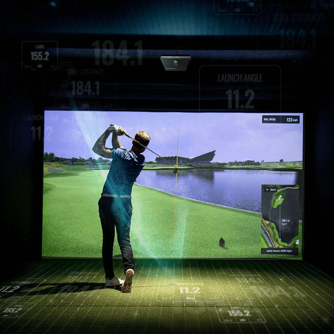 Golfer using Trackman iO in indoor simulator hitting area with real-time ball flight and data overlay